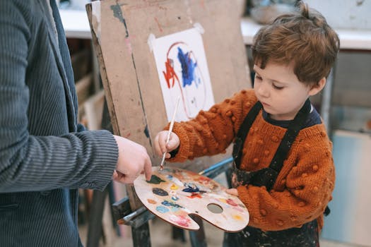 Young boy learning to paint with teacher's guidance during art class.